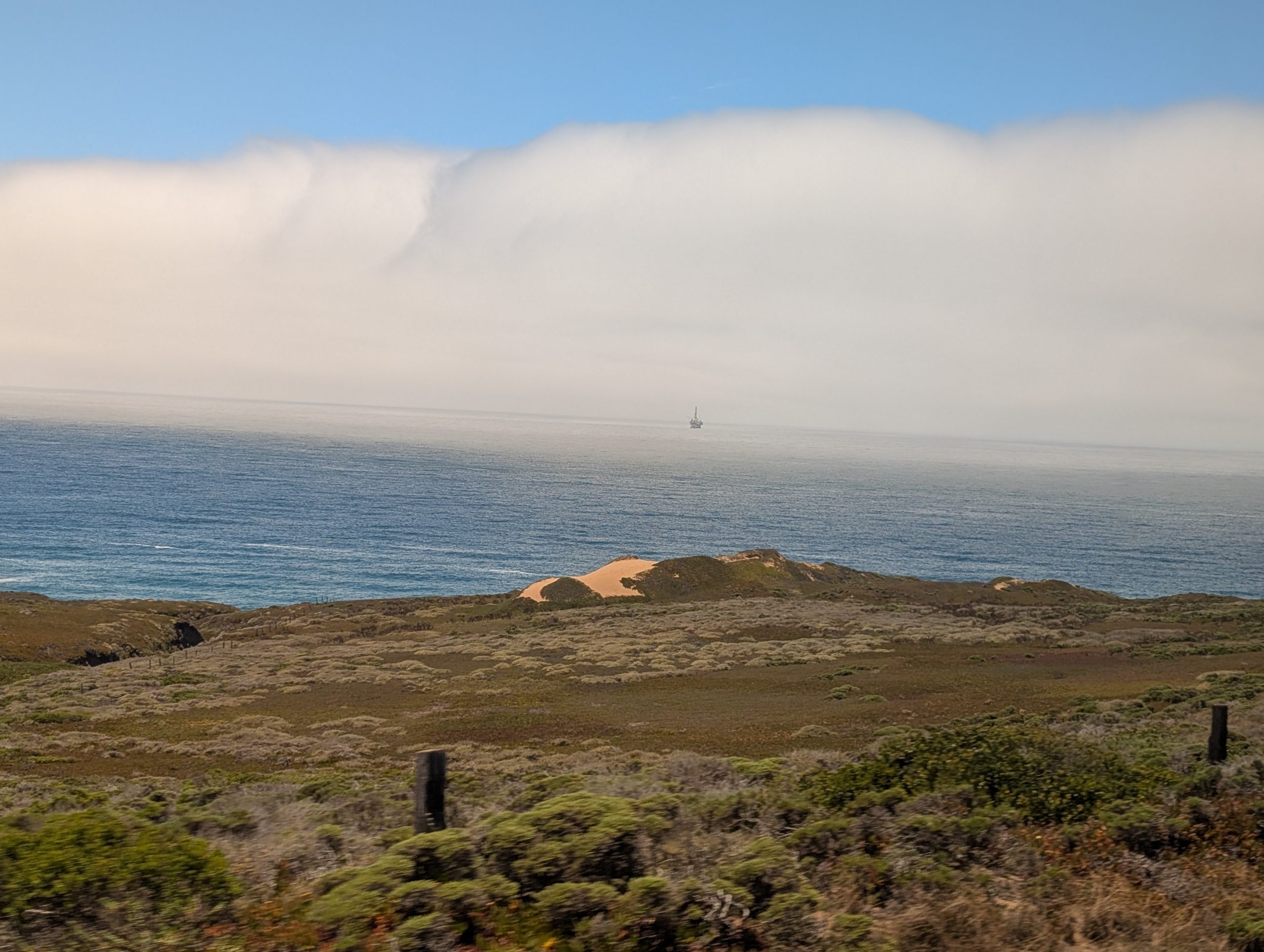 Cloud front envelops offshore oil platform, as seen from the Coast Starlight Amtrak train.